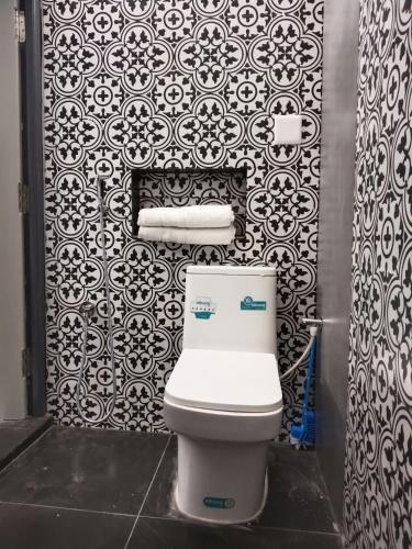 a bathroom with a toilet and a black and white wallpaper at Mithila Homestay in Thanjāvūr