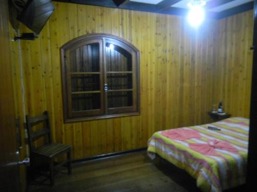 a bedroom with a bed and a window and a chair at Villaggio D'Amore in Monte Verde