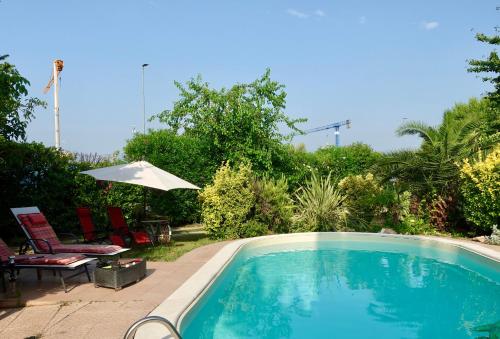 a swimming pool with two chairs and an umbrella at Au Jardin fleuri in San Giovanni Lupatoto