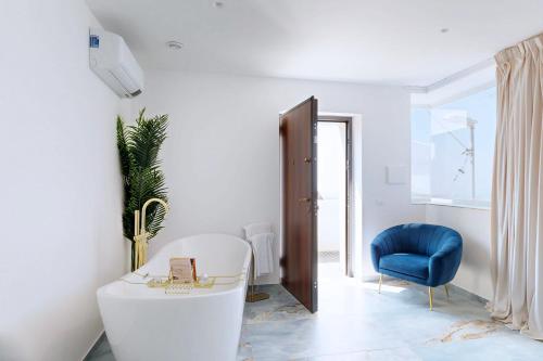 a bathroom with a white tub and a blue chair at Antico Borgo dei Templi in Agrigento