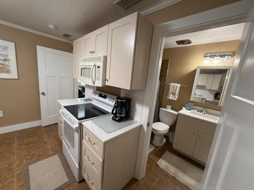 a kitchen with white cabinets and a sink and a toilet at Palm Haven Beach Side Villa in Holmes Beach