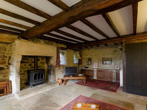 un grand salon avec une cheminée et une table dans l'établissement Highbury Cottage, à Hathersage
