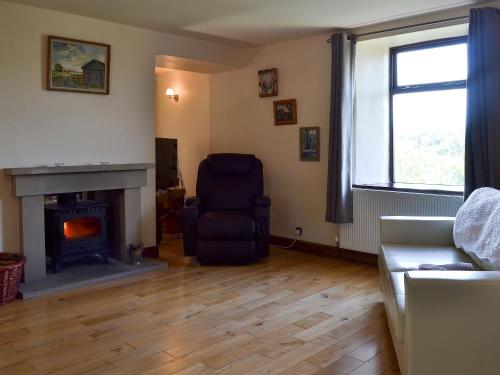 a living room with a chair and a fireplace at Wood Cottage in Whaley Bridge