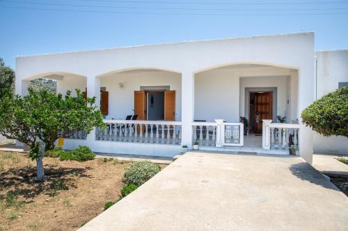 a white house with a porch and trees at Debbie's Holiday Home with sunset in Lakkíon