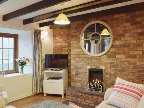 a living room with a brick wall with a fireplace at Ty Capel Seion in Cardigan