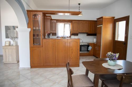 a kitchen with wooden cabinets and a table with chairs at Debbie's Holiday Home with sunset in Lakkíon