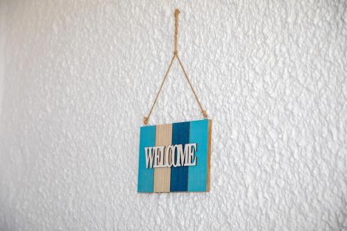 a sign that says welcome hanging on a wall at Debbie's Holiday Home with sunset in Lakkíon