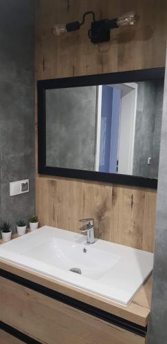 a bathroom with a white sink and a mirror at Nowoczesny apartament z dużym tarasem i widokiem na jezioro in Giżycko
