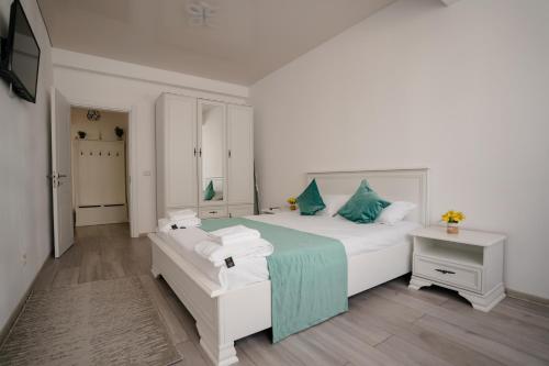 a white bedroom with a large bed with blue pillows at Ana Derol in Năvodari