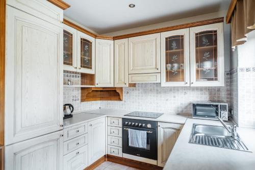 a white kitchen with white cabinets and a sink at Hotel resort Lovecká bašta Strakonice in Strakonice