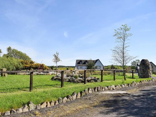 a pasture with a fence and a house in the background at Lawford Lodge in Bonnybridge