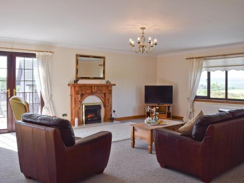 a living room with two couches and a fireplace at Lawford Lodge in Bonnybridge