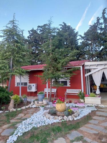 a red house with a garden in front of it at Menƴ's Azure Escape in Dhíkella