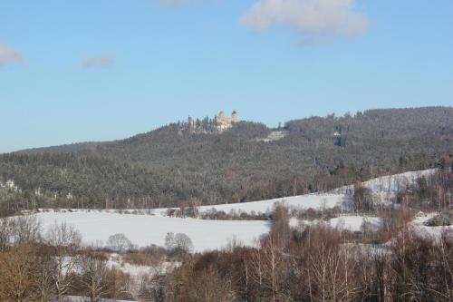 a snow covered hill with a house on top of it at Penzion Na Solné stezce in Kašperské Hory
