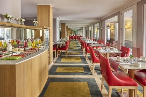 une salle à manger avec des tables et des chaises rouges dans l'établissement Fraser Suites Le Claridge Champs-Elysées, à Paris