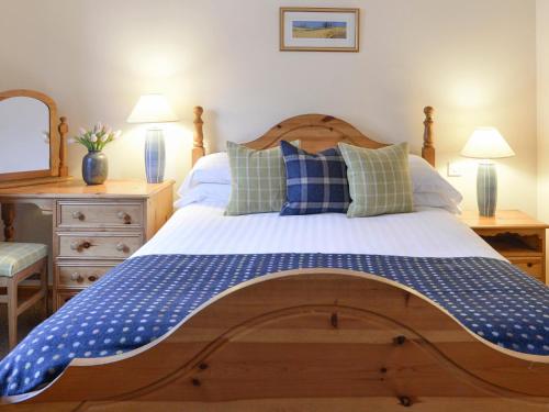 Un dormitorio con una cama grande con almohadas azules y blancas. en Cluny, en Aberfeldy