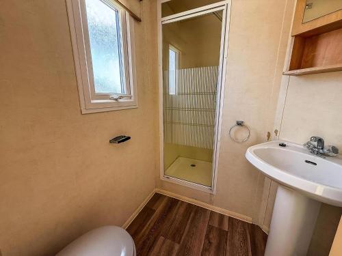 un bagno con lavandino, WC e specchio di Fantastic 4 Berth Caravan In Skegness With Private Hot Tub Ref 96023H a Skegness
