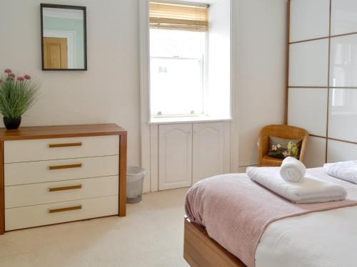 a bedroom with a bed and a dresser and a window at Buckle House in Gatehouse of Fleet