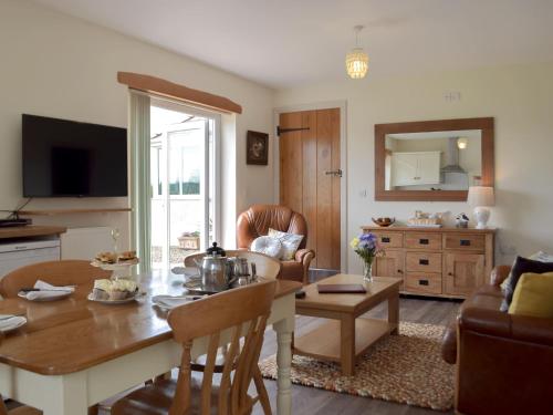 a living room with a table and a dining room at Piglets Cottage in Robeston Wathen