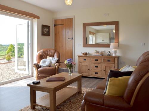a living room with two chairs and a table at Piglets Cottage in Robeston Wathen