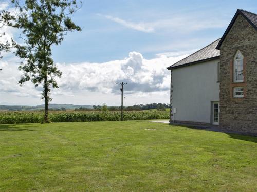 a house with a grass yard next to a building at Swn-Y-Don in Llanstephan