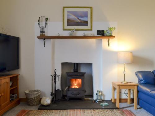 a living room with a fireplace and a blue couch at Tote Cottage in Skeabost