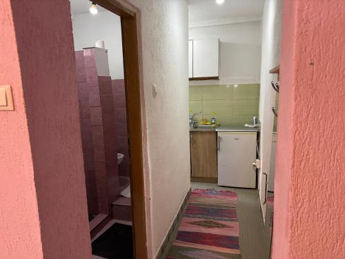 a small kitchen with a pink wall and a doorway at Apartments Jasmin in Goražde