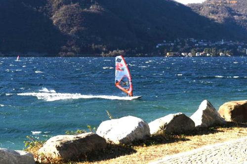 a sailboat in the water near some rocks at A DREAM ON THE LAKE Via Roma in Lierna