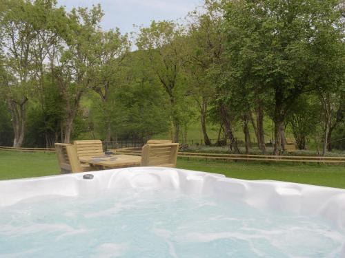 a hot tub in a yard with chairs and a table at Cain Pod Vip in Llanfyllin
