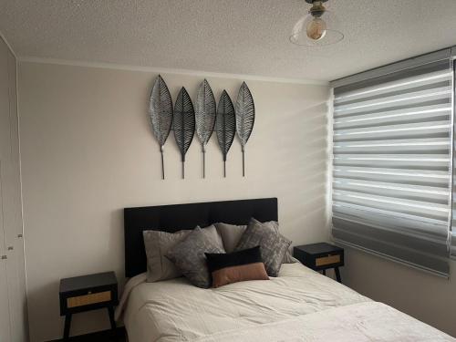 a bedroom with a bed with three feathers on the wall at Departamento Llanquihue Lago in Llanquihue