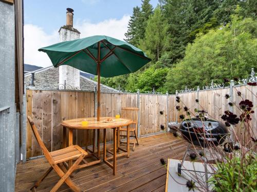 a patio with a table and an umbrella on a deck at The Granary - Uk34899 in Dunira