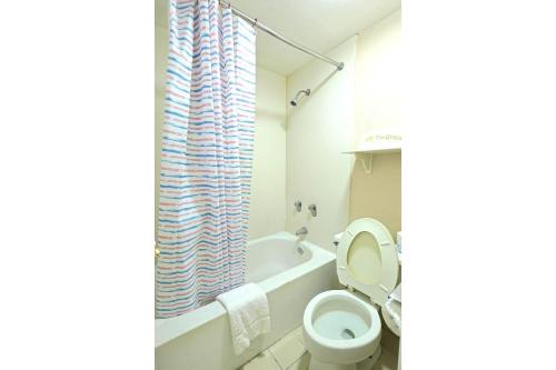 a bathroom with a toilet and a bath tub at The Grand by Capital O Texarkana I-30 in Texarkana - Texas