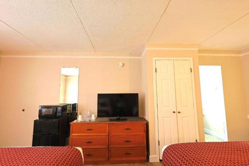 a living room with a television and a dresser with a dresserngth at The Grand by Capital O Texarkana I-30 in Texarkana - Texas