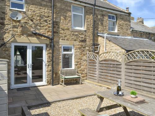 a patio with a wooden table and a building at Dolly's Cottage in Ovingham