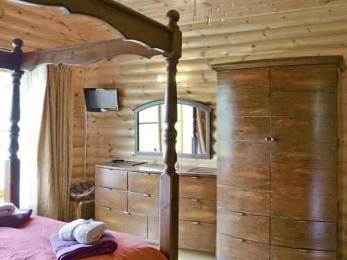 1 dormitorio con cama y espejo en una cabaña en Ashknowe Log Cabin - S4590, en Glenfarg