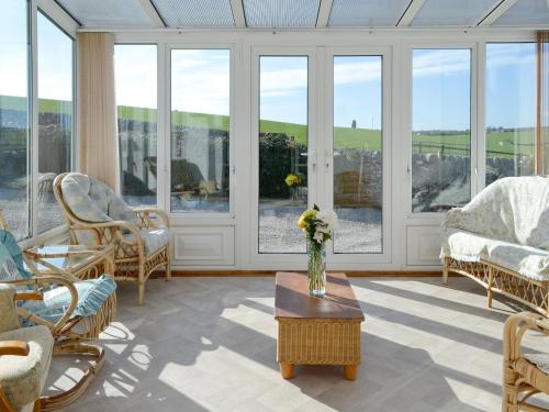 a living room with windows and a vase of flowers on a table at Bel-Mar in Whithorn