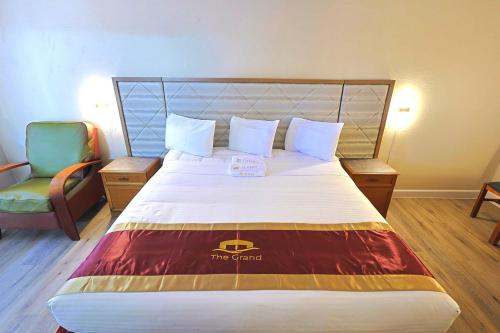 a hotel room with a large bed and a chair at The Grand by Capital O Texarkana I-30 in Texarkana - Texas