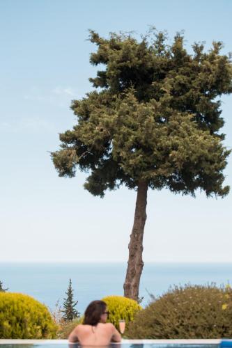 a woman sitting in a pool next to a tree at BlueSkyline Owner's Listing, By Hellocrete in Chania Town