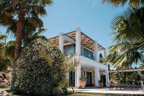 a white house with palm trees in front of it at BlueSkyline Owner's Listing, By Hellocrete in Chania Town