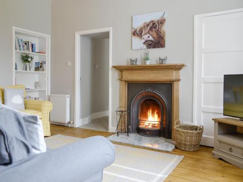 a living room with a fireplace and a couch at The Old School House Cottage in Coupar Angus