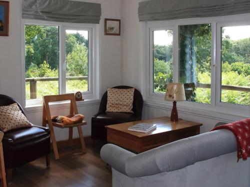 a living room with a couch and chairs and windows at The Garden House - Uk10987 in Llandogo
