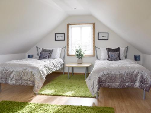 two beds in a attic bedroom with a green rug at The Lodge At Lochnagar in Peat Inn 