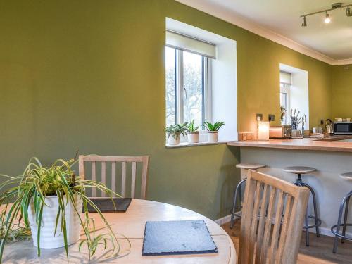 a dining room with a table and some plants at Meadow Cottage in Gowerton