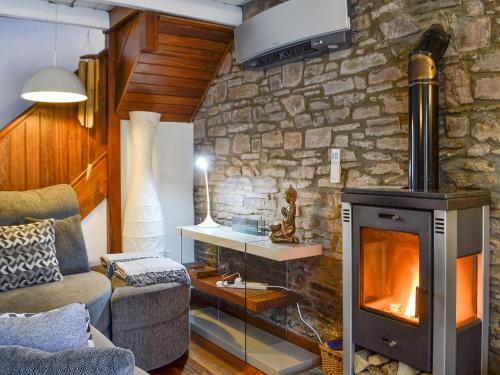 a living room with a stone wall with a fireplace at The Cart House in Merthyr Cynog