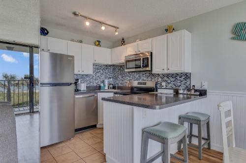 a kitchen with white cabinets and a stainless steel refrigerator at 0210 Sun-Kissed Memories condo in Carolina Beach