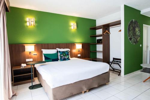 a bedroom with a large bed and a green wall at Ibis Styles Cayenne Centre Amazonia in Cayenne