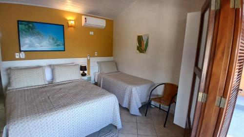 a small room with two beds and a chair at Pousada Do Forte in Paraty