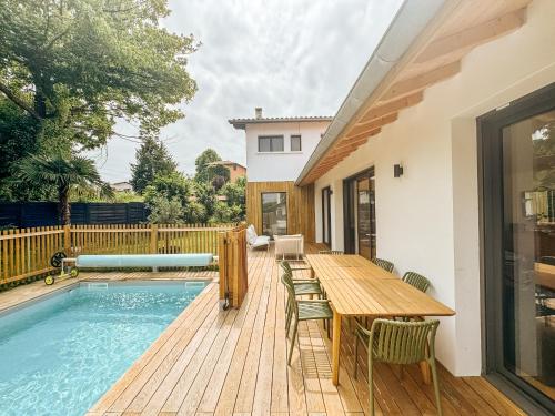 une terrasse en bois avec une table et une piscine dans l'établissement Designer villa with pool, à Bayonne