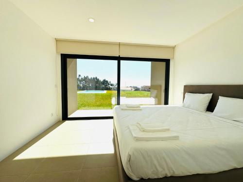 a bedroom with a white bed and a large window at Quintinha Pilares da Terra in Marinhas