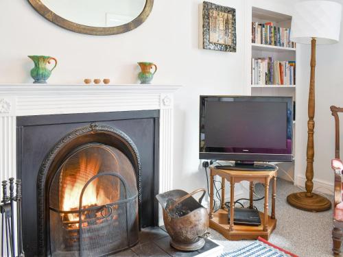 un salon avec une cheminée et une télévision dans l'établissement Seaton Cottage, à Collieston